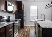 Thumbnail 20 of 37 - a kitchen with granite countertops and dark wood cabinets  at RoCo Apartments, Fargo, North Dakota, 58102