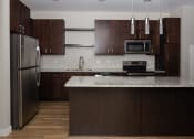 Thumbnail 22 of 37 - a kitchen with dark wood cabinets and a white counter top  at RoCo Apartments, Fargo, ND 58102