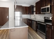 Thumbnail 26 of 37 - a kitchen with dark wood cabinets and stainless steel appliances  at RoCo Apartments, Fargo, North Dakota 58102