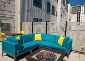 Thumbnail 67 of 84 - a patio with a blue couch and yellow pillows at The Landing at 1001 NP, Fargo, ND 58102