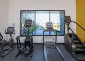 Thumbnail 46 of 84 - a treadmill and three treadmills in a gym with a large window at The Landing at 1001 NP, Fargo, ND 58102