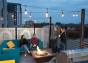 Thumbnail 77 of 84 - a group of people sitting around a fire pit on a rooftop patio at The Landing at 1001 NP, Fargo, ND 58102