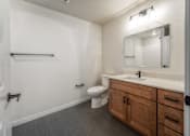 Thumbnail 16 of 36 - A bathroom with a toilet, sink, and mirror. at Unite Apartments, North Dakota