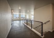 Thumbnail 4 of 36 - A long hallway with a black railing and a window with a view. at Unite Apartments, North Dakota, 58103
