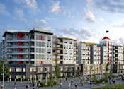 Thumbnail 40 of 43 - A striking exterior view here at Experience at Epicenter showcasing a multi-story modern apartment community with mixed materials, bold red vertical accents, and curved balconies. Ground-level retail spaces, landscaped walkways, and outdoor seating activate the streetscape, while residents and pedestrians gather beneath a partly cloudy sky.