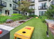 Thumbnail 21 of 86 - an apartment yard with a yellow bench and a grill