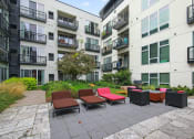 Thumbnail 14 of 86 - an outdoor area with lounge chairs in front of an apartment building