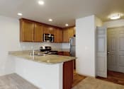 Thumbnail 14 of 32 - A bright kitchen here at Windsong featuring warm wood cabinetry, spacious breakfast bar, and sleek stainless steel appliances. Neutral finishes and open layout create an inviting, functional space perfect for cooking and entertaining.
