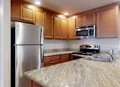 Thumbnail 15 of 32 - A bright kitchen here at Windsong featuring warm wood cabinetry, sleek stainless steel appliances, and spacious granite countertops. Clean finishes and efficient layout create a welcoming, functional space ideal for everyday cooking and dining.