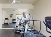 Thumbnail 18 of 32 - A fitness center here at Windsong featuring cardio machines, free weights, and a full wall mirror. Bright and motivating, this well-equipped space offers a convenient area for energizing workouts.