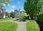 Thumbnail 26 of 32 - A landscaped courtyard here at Windsong featuring lush green lawns, curved walking paths, and mature trees. This bright and inviting outdoor space offers scenic surroundings, well-maintained greenery, and a peaceful setting for relaxing strolls.