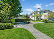 Thumbnail 24 of 32 - A landscaped outdoor courtyard here at Windsong featuring green lawns, curved walking paths, and mature trees. This bright and inviting setting offers peaceful surroundings, well-maintained greenery, and a pleasant space for relaxing strolls outdoors.