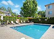 Thumbnail 22 of 32 - A refreshing outdoor pool here at Windsong surrounded by lush greenery and charming apartment buildings. This bright and inviting space features clear blue water, comfortable lounge chairs, and a peaceful atmosphere perfect for relaxing on sunny days.