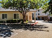 Thumbnail 28 of 32 - A leasing office exterior here at Windsong featuring a charming single-story building with a covered entry, mature shade tree, and manicured landscaping. This inviting and well-kept space offers convenient access and a welcoming community atmosphere.