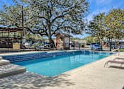 Thumbnail 18 of 19 - Modern swimming pool with lounge seating at Sierra Ranch Apartments in San Antonio, TX.