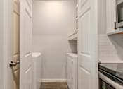 Thumbnail 36 of 42 - A white kitchen with a door open.