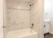 Thumbnail 38 of 42 - A white bathroom with a marble tile wall.