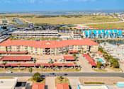 Thumbnail 42 of 42 - A large building with a red roof is surrounded by a parking lot and palm trees.