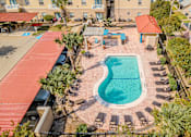 Thumbnail 39 of 42 - An aerial view of a pool surrounded by a red roof and palm trees.