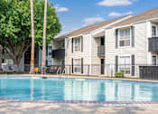 Thumbnail 5 of 11 - A swimming pool in front of a building with a red brick border.