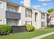 Thumbnail 10 of 11 - A row of beige townhouses with green lawns in front.