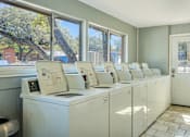 Thumbnail 7 of 7 - A row of washing machines are lined up in a room.