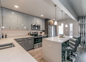 Thumbnail 15 of 30 - Designer kitchen with quartz countertops and stainless-steel appliances in Dallas apartment