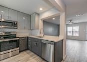 Thumbnail 19 of 30 - Designer kitchen with quartz countertops and stainless-steel appliances in Dallas apartment