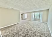 Thumbnail 3 of 13 - Large living room with grey carpet and bright natural light at Greenbriar Place 55+ Senior Apartments in Corpus Christi.