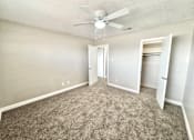 Thumbnail 5 of 13 - Bedroom with ceiling fan and carpet flooring at Greenbriar Place 55+ Apartments in Corpus Christi.