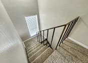 Thumbnail 6 of 19 - A staircase with a metal railing and carpeted steps.