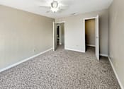 Thumbnail 7 of 19 - A room with a ceiling fan and carpeted floor.