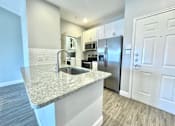 Thumbnail 1 of 25 - A kitchen with a granite countertop and stainless steel appliances.