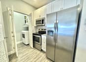 Thumbnail 2 of 25 - A kitchen with a refrigerator, oven, and microwave.