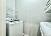 Thumbnail 15 of 25 - A white dryer is in a laundry room with a white washing machine.