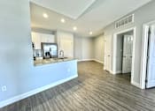 Thumbnail 4 of 25 - A spacious room with wooden flooring and white walls.
