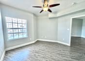 Thumbnail 7 of 25 - A room with a ceiling fan and a window.