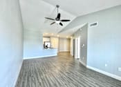 Thumbnail 8 of 25 - A spacious room with a ceiling fan and wooden flooring.