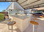 Thumbnail 9 of 30 - a bar with wooden stools and a grill on a patio