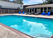 Thumbnail 12 of 17 - A swimming pool with blue chairs around it.