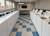 Thumbnail 14 of 17 - A laundromat with rows of washers and dryers.