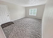 Thumbnail 2 of 17 - A room with a door, window, and carpeted floor.