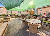 Thumbnail 3 of 5 - A wooden deck with a table and chairs under a green canopy.