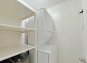 Thumbnail 13 of 15 - A white washing machine sits in a small laundry room.