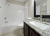 Thumbnail 14 of 15 - A bathroom with a white toilet and a marble counter top.