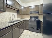 Thumbnail 11 of 15 - A kitchen with a black stove and black cabinets.