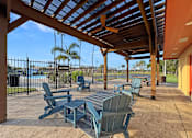 Thumbnail 9 of 15 - A patio with a table and chairs under a roof.