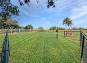Thumbnail 6 of 15 - A baseball field with a fence and a trash can.
