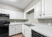Thumbnail 25 of 28 - Kitchen with white cabinets and black appliances at Verano Oaks Apartments