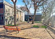Thumbnail 14 of 28 - Corn hole area with tables under trees at Verano Oaks Apartments in Hurst, TX